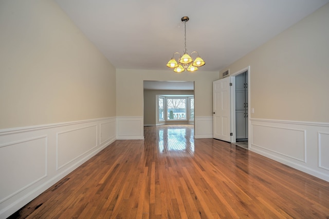 4238 Still Meadow Ln, West Bloomfield, MI 48323 - unfurnished dining area featuring a chandelier, hardwood / wood-style flooring, a wainscoted wall, and a decorative wall