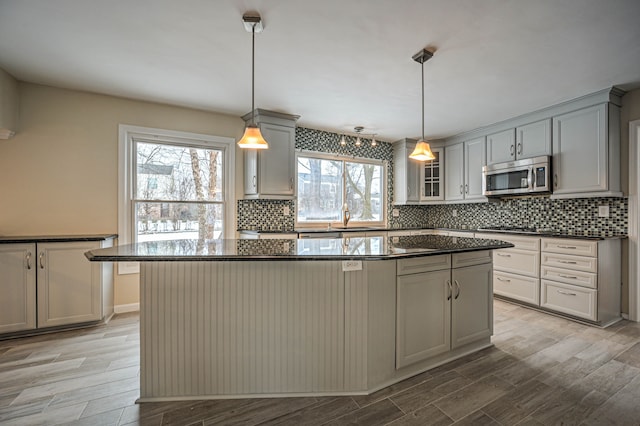 4238 Still Meadow Ln, West Bloomfield, MI 48323 - kitchen with stainless steel microwave, light wood-type flooring, a kitchen island, backsplash, and black stovetop