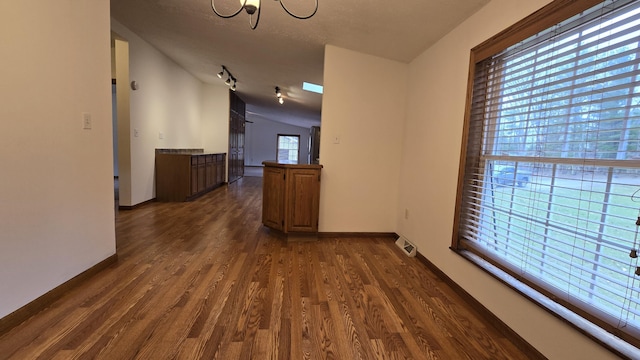 hall featuring visible vents, baseboards, a notable chandelier, and dark wood-style flooring