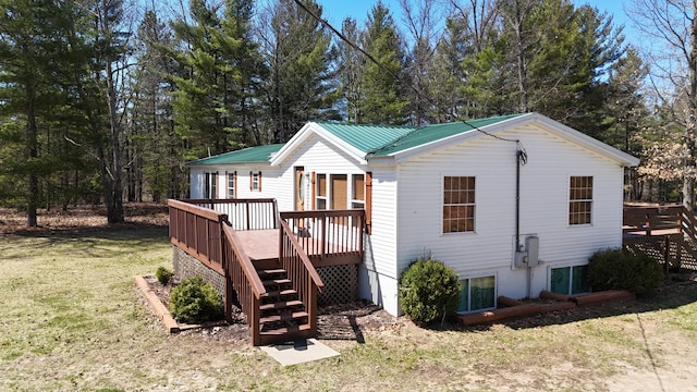 view of front of home featuring a front lawn, stairway, a deck, and metal roof