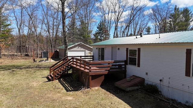 exterior space featuring a deck, metal roof, an outbuilding, a lawn, and a garage