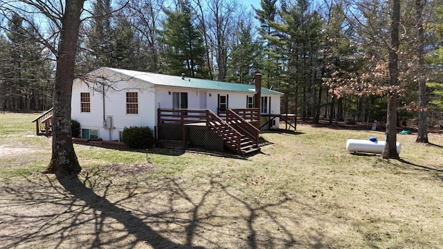 view of front of property with a front yard, stairs, metal roof, and a deck