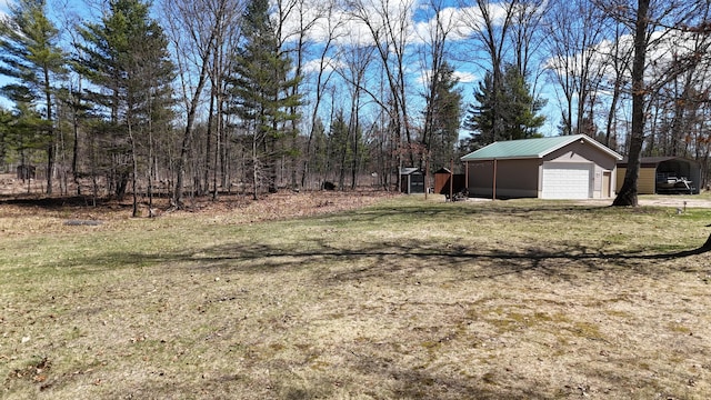 view of yard featuring an outbuilding, a carport, and a garage