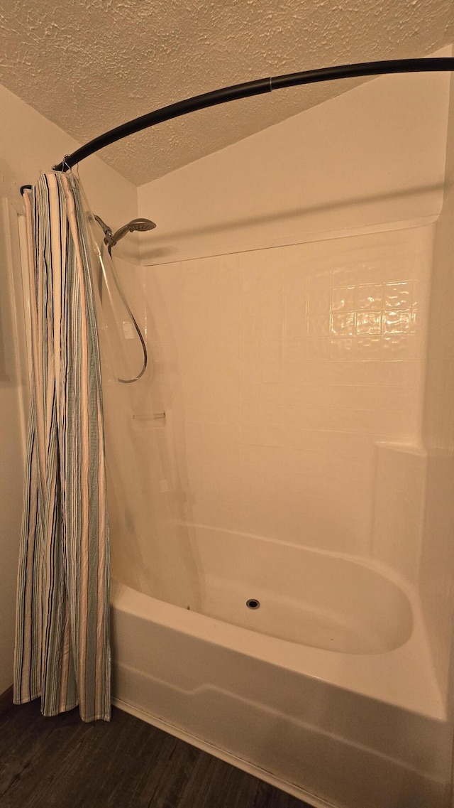bathroom featuring shower / bath combo, wood finished floors, and a textured ceiling