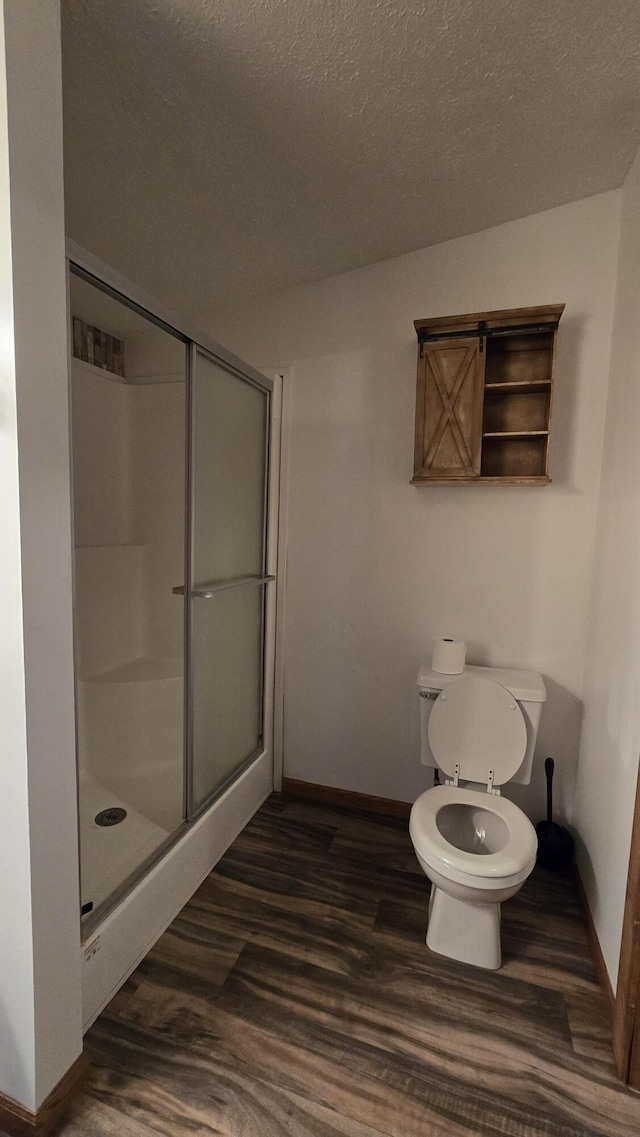 full bath featuring wood finished floors, baseboards, a textured ceiling, and a stall shower