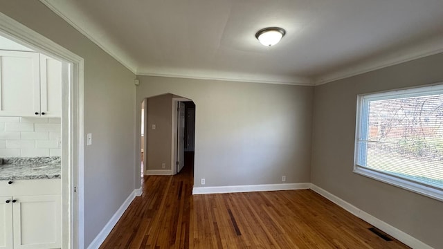 5051 Courville St, Detroit, MI 48224 - empty room featuring visible vents, arched walkways, dark wood-type flooring, crown molding, and baseboards