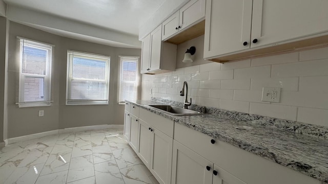 5051 Courville St, Detroit, MI 48224 - kitchen featuring white cabinets, marble finish floor, backsplash, a sink, and baseboards