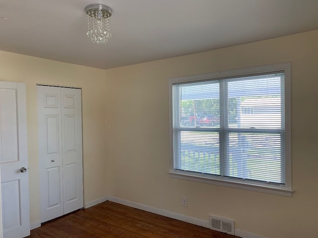 702 Oda St, Davison, MI 48423 - unfurnished bedroom featuring baseboards, dark wood-style flooring, a chandelier, and a closet