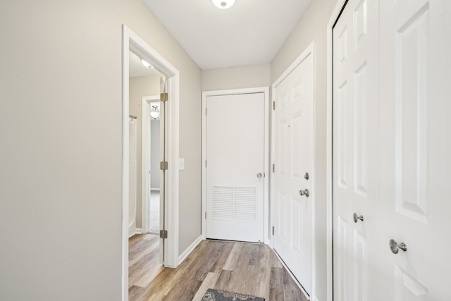 corridor featuring light wood-style flooring and baseboards