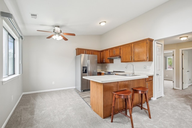 kitchen with stainless steel fridge with ice dispenser, a sink, light carpet, a peninsula, and vaulted ceiling