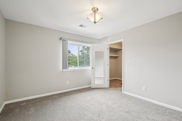 unfurnished bedroom featuring carpet floors, baseboards, a spacious closet, and a closet