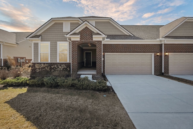 view of front facade featuring brick siding, an attached garage, driveway, and a shingled roof