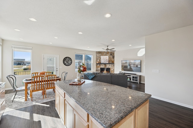 kitchen featuring recessed lighting, dark wood finished floors, a stone fireplace, light brown cabinets, and ceiling fan