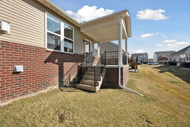 view of side of property featuring a lawn, brick siding, and a residential view