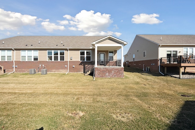 back of property with brick siding, cooling unit, a lawn, and stairway