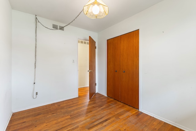 spare room featuring baseboards, visible vents, and wood finished floors