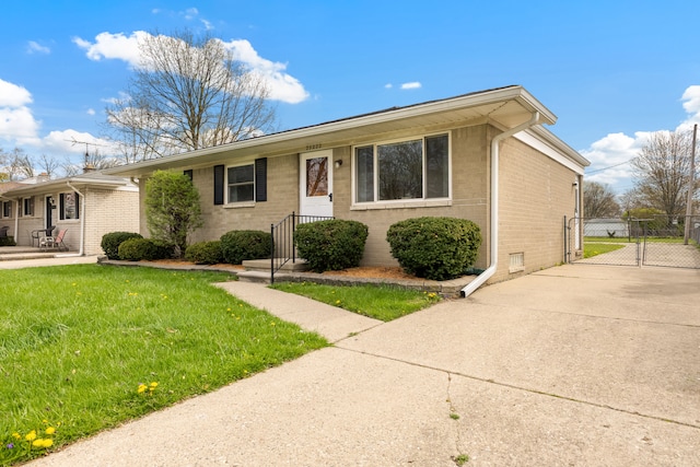 view of front of property with a front lawn, a gate, driveway, brick siding, and fence