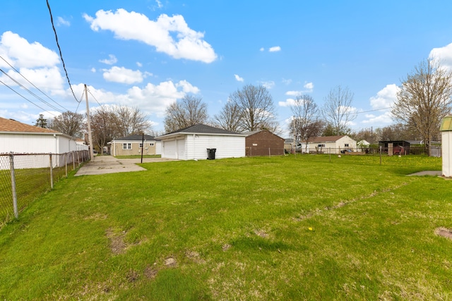 view of yard featuring a garage, fence, and an outdoor structure