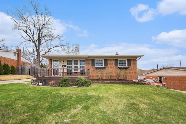 back of property featuring brick siding, a lawn, a porch, and fence