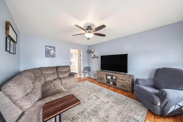 living room with wood finished floors, a ceiling fan, and baseboards