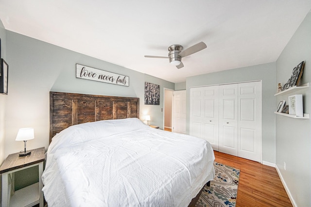 bedroom with baseboards, a ceiling fan, wood finished floors, and a closet