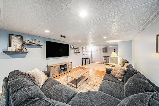 living area featuring baseboards, a paneled ceiling, and wood finished floors