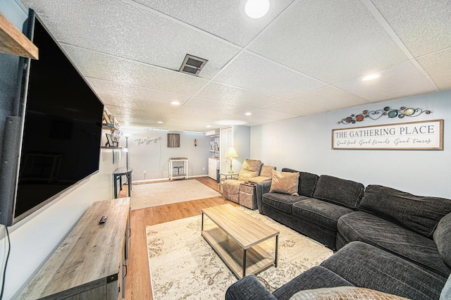living area featuring wood finished floors and a paneled ceiling