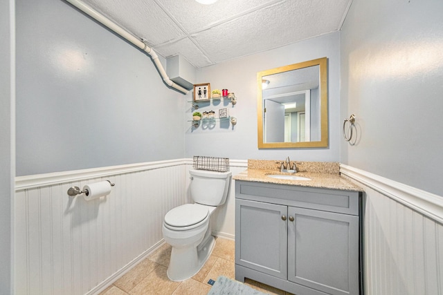 bathroom featuring wainscoting, tile patterned floors, vanity, and toilet