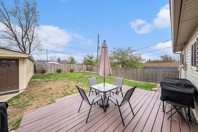 deck featuring a lawn, grilling area, outdoor dining space, and a fenced backyard