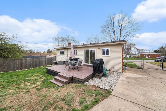 back of house featuring a lawn, a wooden deck, a fenced backyard, and a gate