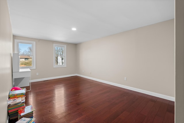 spare room with recessed lighting, baseboards, and dark wood-style flooring
