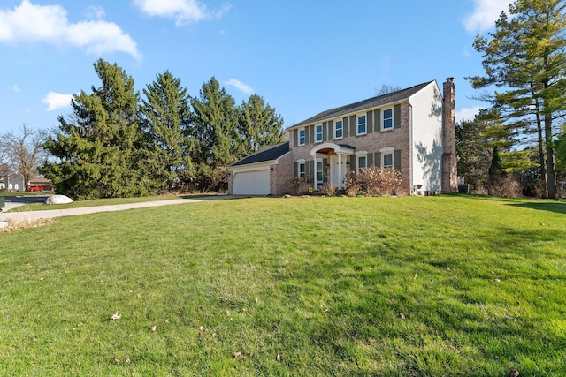colonial house featuring driveway, a chimney, brick siding, an attached garage, and a front yard