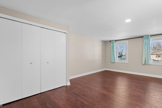 unfurnished bedroom with recessed lighting, wood finished floors, a closet, and baseboards
