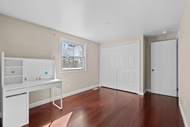 unfurnished bedroom with hardwood / wood-style floors, baseboards, and a closet