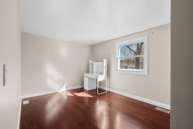 spare room with baseboards, visible vents, and hardwood / wood-style flooring