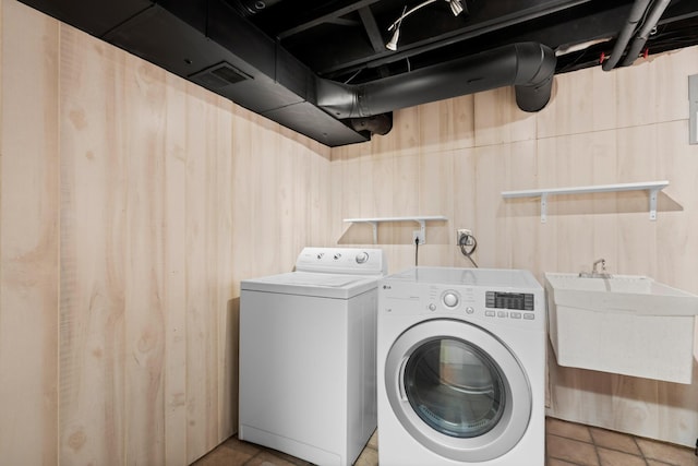 clothes washing area featuring washing machine and clothes dryer, visible vents, a sink, and laundry area