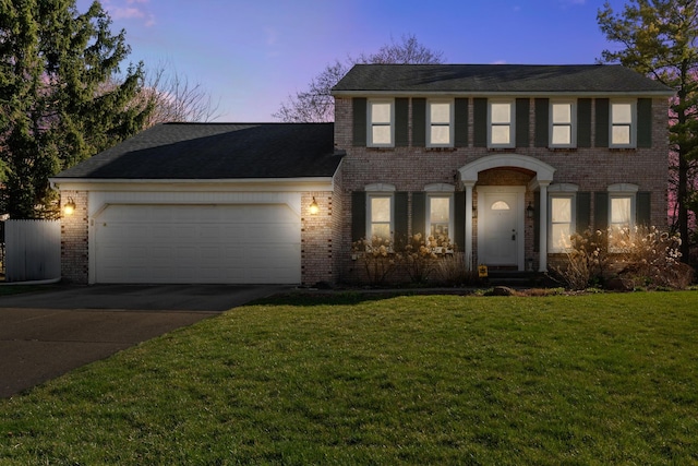 colonial inspired home with brick siding, a yard, an attached garage, and concrete driveway