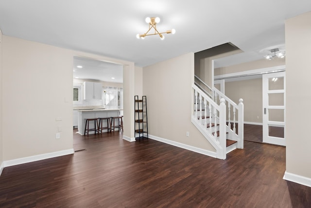 interior space with dark wood-style floors, an inviting chandelier, visible vents, baseboards, and stairs