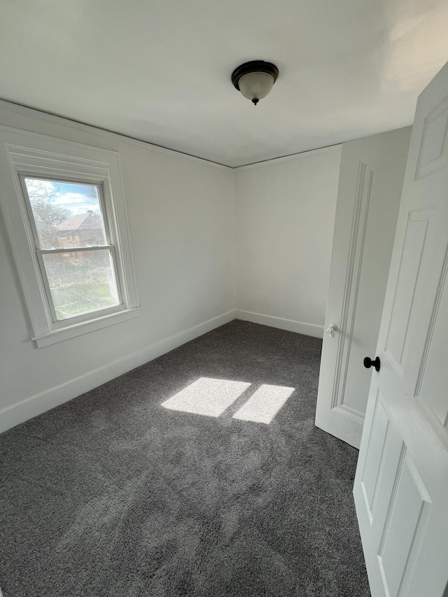 empty room with baseboards and dark carpet