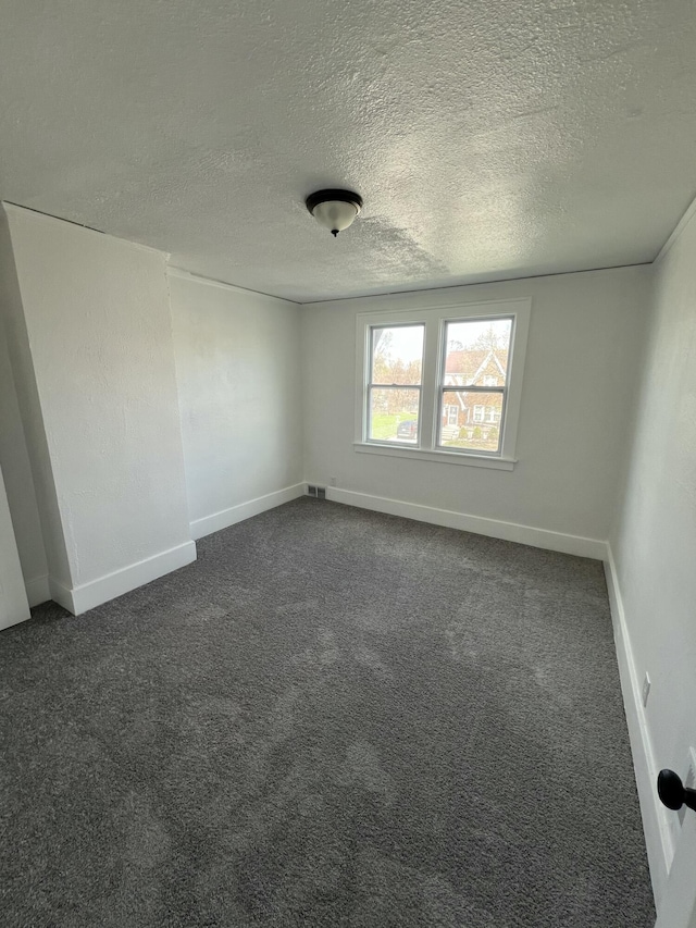 unfurnished room with dark colored carpet, a textured ceiling, and baseboards