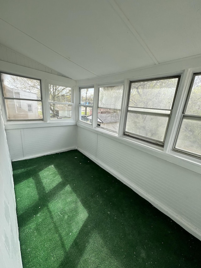 unfurnished sunroom featuring carpet, a healthy amount of sunlight, and lofted ceiling