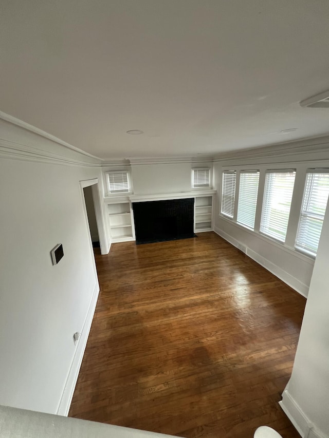 unfurnished living room with a fireplace with flush hearth, baseboards, crown molding, and dark wood-type flooring