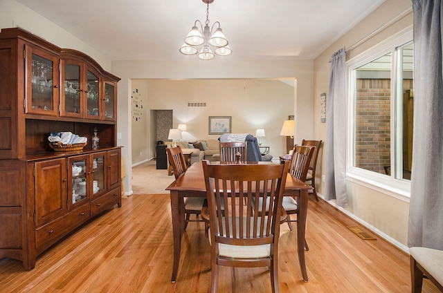 dining area featuring light wood-style floors, baseboards, a chandelier, and visible vents