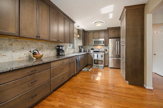 kitchen featuring light wood-style floors, a sink, decorative backsplash, and stainless steel appliances