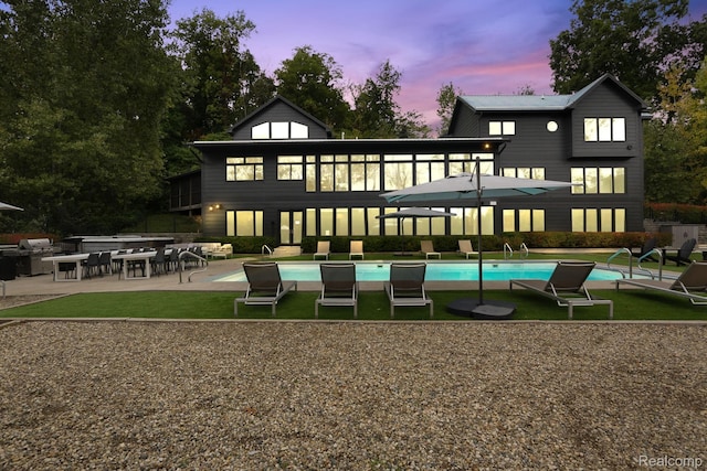 10630 Garr Rd, Berrien Springs, MI 49103 - back of house at dusk with a patio area, an outdoor pool, and a lawn