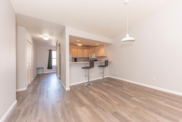 1005 E Duncan St Unit 2D, Manchester, MI 48158 - kitchen featuring light wood-style floors, baseboards, a breakfast bar area, and white appliances