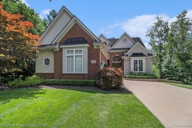 view of front of home featuring stone siding, a standing seam roof, brick siding, and a front yard