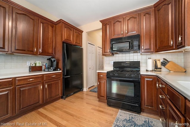 kitchen featuring backsplash, light wood-style floors, light countertops, and black appliances