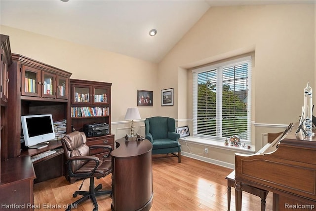 office area with high vaulted ceiling and light wood-style floors