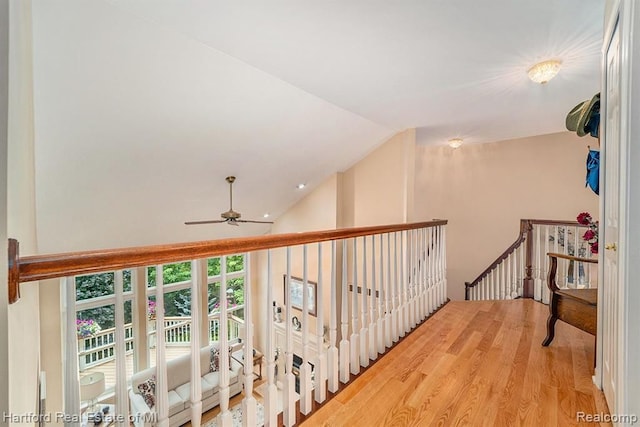 hallway with wood finished floors, high vaulted ceiling, and an upstairs landing
